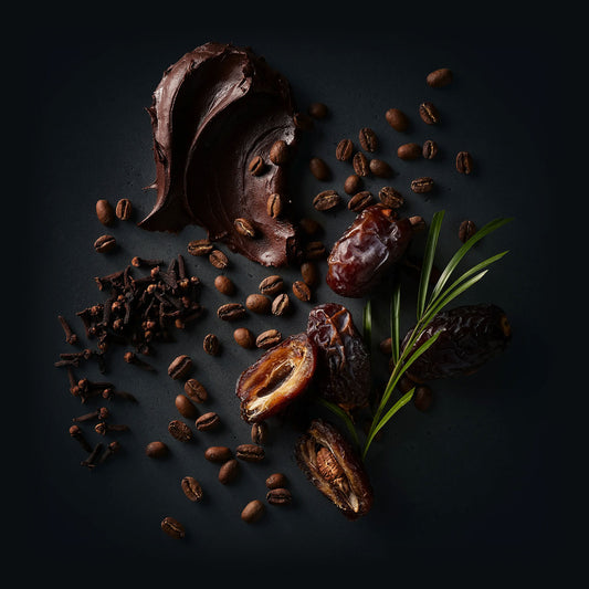 Kambera Coffee by Ninety Plus Coffee. A spread of roasted coffee beans with food items that represent that flavor notes of dark chocolate, date, and clove. 