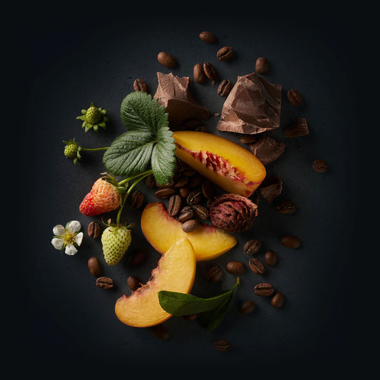 Perci Coffee by Ninety Plus Coffee.  A spread of roasted coffee beans with food items that represent that flavor notes of strawberry, milk chocolate, and peach. 