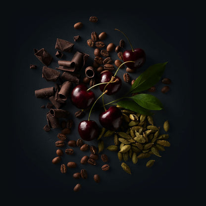 Ruby Coffee by Ninety Plus Coffee.  A spread of roasted coffee beans with food items that represent that flavor notes of milk chocolate, black cherry, and cardamom. 