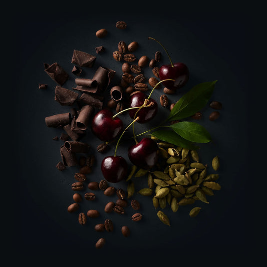 Ruby Coffee by Ninety Plus Coffee.  A spread of roasted coffee beans with food items that represent that flavor notes of milk chocolate, black cherry, and cardamom. 
