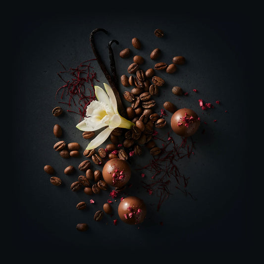 Tigre Coffee by Ninety Plus Coffee.  A spread of roasted coffee beans with food items that represent that flavor notes of raspberry truffle, vanilla, and safron. 